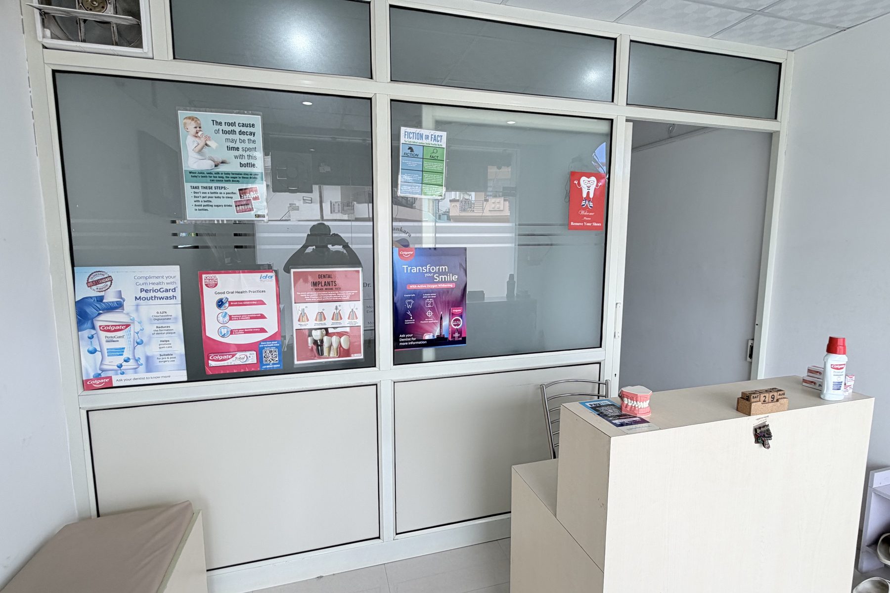 The reception area of the clinic, with seating and oral health information displayed on the partition beside the desk.